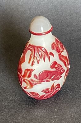 a small red and white vase with a bird on it