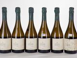 six bottles of wine are lined up in a row on a white surface