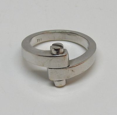 une bague en argent ornée d'une croix, posée sur un fond blanc