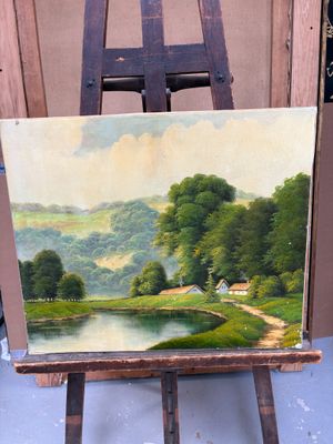une peinture à l'huile représentant un paysage sur un chevalet, avec une maison au loin