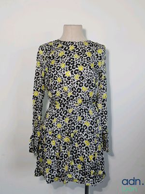 une robe noire et blanche ornée de fleurs jaunes, présentée sur un mannequin