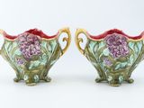 pair of green and pink vases with flowers on them on a white surface