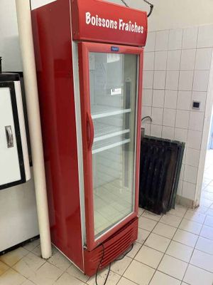 un réfrigérateur rouge posé au milieu d'un sol carrelé