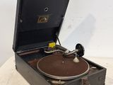 un vieux tourne-disque posé sur une table près d'un mur blanc