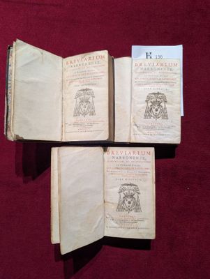 trois vieux livres posés sur une table recouverte d'un tissu rouge