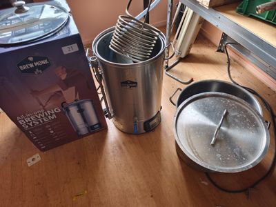 un seau en métal contenant un fouet, à côté d'une boîte contenant un fouet