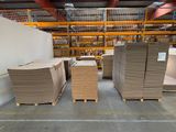 Plusieurs piles de cartons sont empilées sur des palettes dans un entrepôt