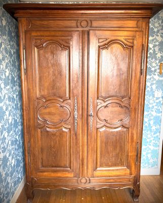 a wooden armoire in the corner of a room