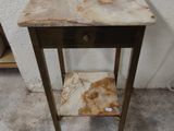 une petite table avec un tiroir, placée contre un mur