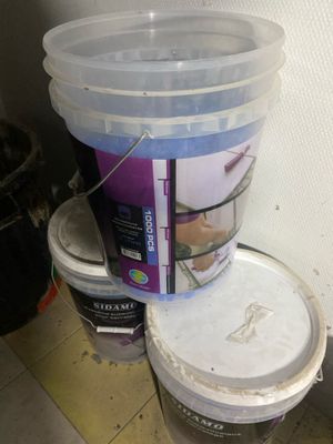 two buckets of paint sitting on the floor next to each other