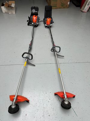 a couple of lawn mowers sitting on top of a garage floor