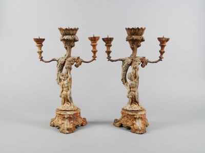 une paire de chandeliers en bois sculpté, ornés chacun d'une figurine