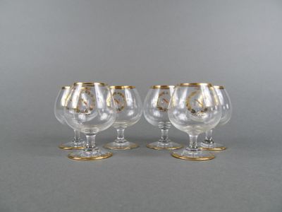 three clear wine glasses with gold rims on a gray surface