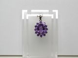 un gros plan d'un collier orné d'une fleur violette