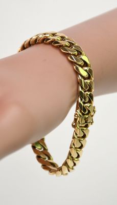 un gros plan sur la main d'une personne portant un bracelet en or