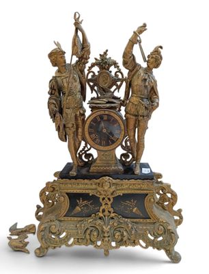 une horloge en or surmontée de statues