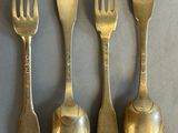 four spoons and a fork are lined up on a table