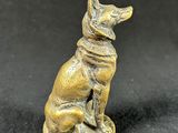 a small bronze statue of a dog sitting on top of a table