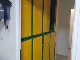 yellow lockers are lined up in a narrow hallway with a bag hanging on the wall