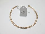 a close up of a gold chain bracelet with a tag on it