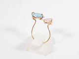un gros plan d'une bague en or sertie de deux pierres bleues et roses