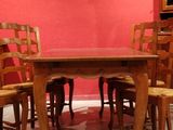 a dining room table and chairs in front of a red wall