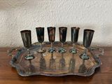 un plateau en argent sur lequel sont posés cinq verres, posé sur une table en bois