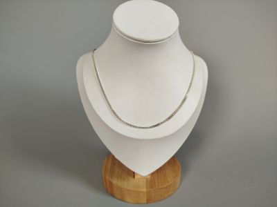 silver chain necklace on a mannequin on a wooden stand