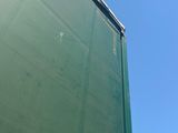 a truck that is driving down the road with a green tarp covering it