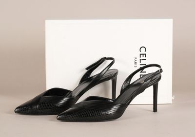 une paire de chaussures noires à talons hauts, avec une boîte en arrière-plan