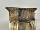 a silver vase with a mirror in it on a table