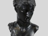 a bronze bust of a woman wearing a headband on top of a wooden pedestal