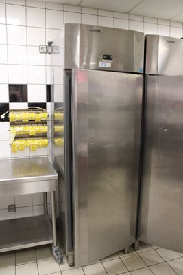 des réfrigérateurs en acier inoxydable dans une cuisine professionnelle dotée d'un sol en carrelage blanc