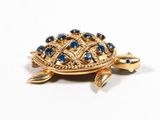 a gold turtle brooch with blue stones on it