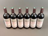 six bottles of wine are lined up in a row on a table