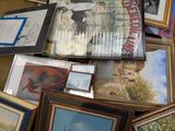 a pile of framed and unframed pictures on the floor