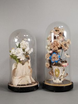 two glass cloches with flowers inside of them