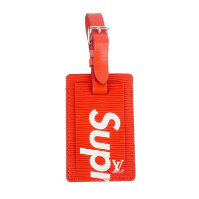 red supreme luggage tag with white supreme logo on it