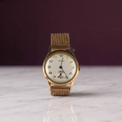 une montre-bracelet en or posée sur une surface en marbre