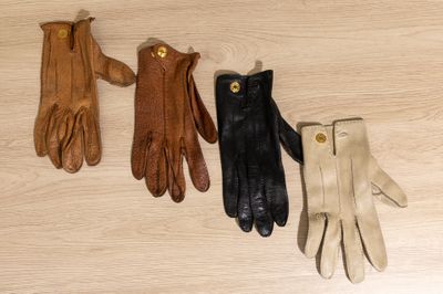 three pairs of leather gloves sitting on top of a wooden floor