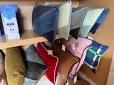 many different colored pillows on a shelf in a room