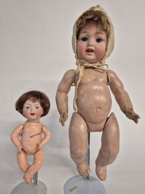 two old dolls that are sitting next to each other