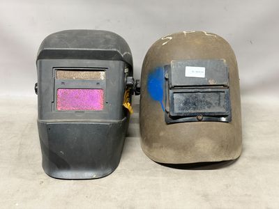 deux casques de soudage posés l'un à côté de l'autre sur une table