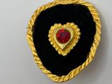 a close up of a heart shaped brooch with a red stone in the center
