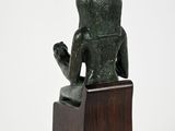 statue of a cat sitting on a wooden base on a white background
