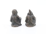 two figurines of a man and a woman sitting on a white surface