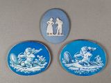 trois assiettes bleues et blanches ornées de personnages, posées sur une table