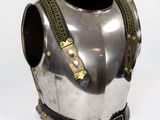 une armure argentée et dorée exposée sur un socle blanc