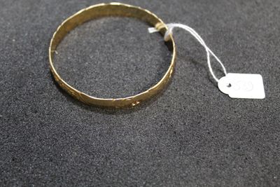 a close up of a gold bracelet with a tag on it