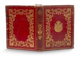 un vieux livre rouge aux bords dorés et orné d'un emblème doré sur la couverture